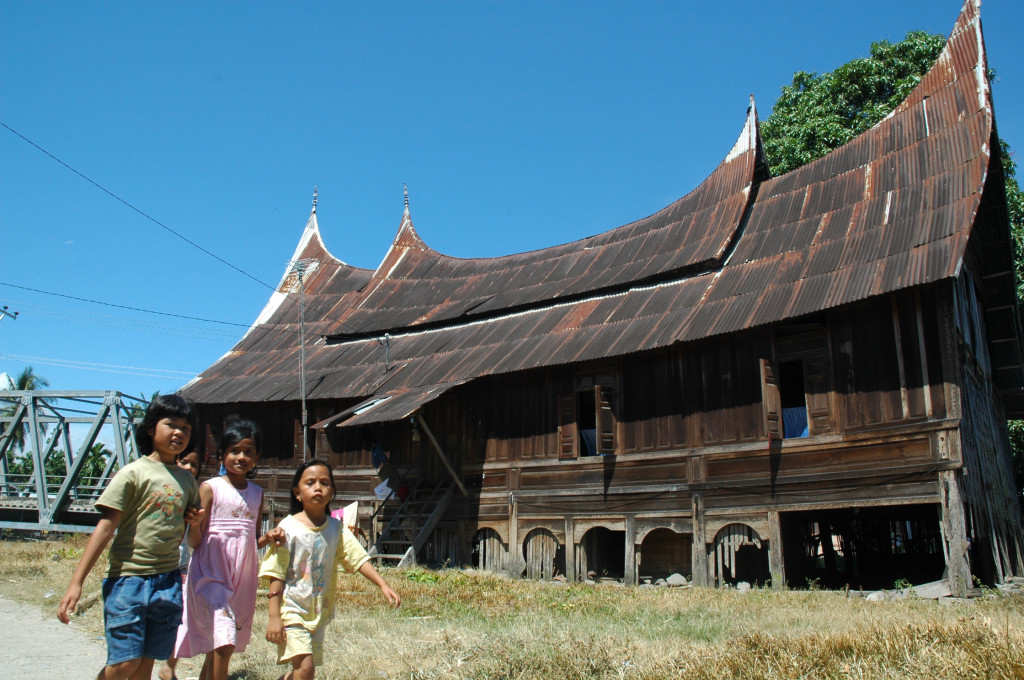 children running in front of a Padang house, Sumatra